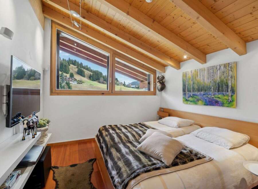This cozy bedroom features a stunning view of the surrounding landscape through its unique angled windows.