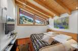 This cozy bedroom features a stunning view of the surrounding landscape through its unique angled windows.