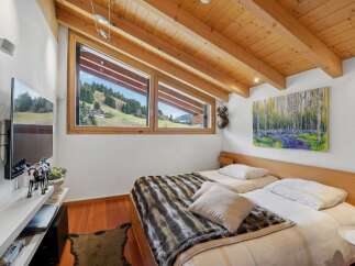 This cozy bedroom features a stunning view of the surrounding landscape through its unique angled windows.
