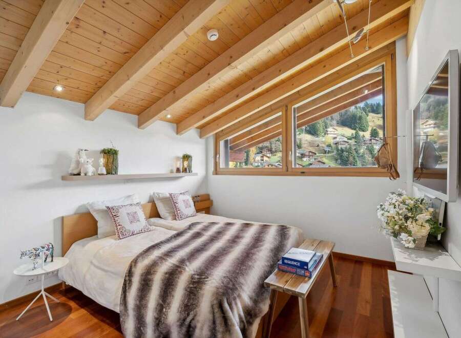 Experience the charm of this cozy bedroom, featuring a stunning wooden ceiling and a picturesque view.