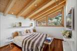 Experience the charm of this cozy bedroom, featuring a stunning wooden ceiling and a picturesque view.