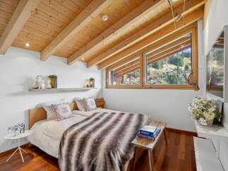 Experience the charm of this cozy bedroom, featuring a stunning wooden ceiling and a picturesque view.