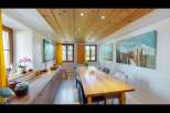 This charming dining room features a warm wooden ceiling and a long, inviting wooden table, perfect for gatherings.