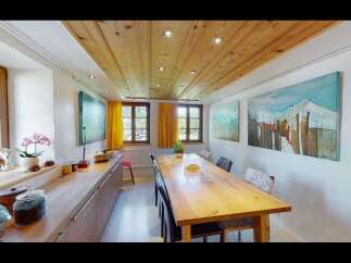 This charming dining room features a warm wooden ceiling and a long, inviting wooden table, perfect for gatherings.