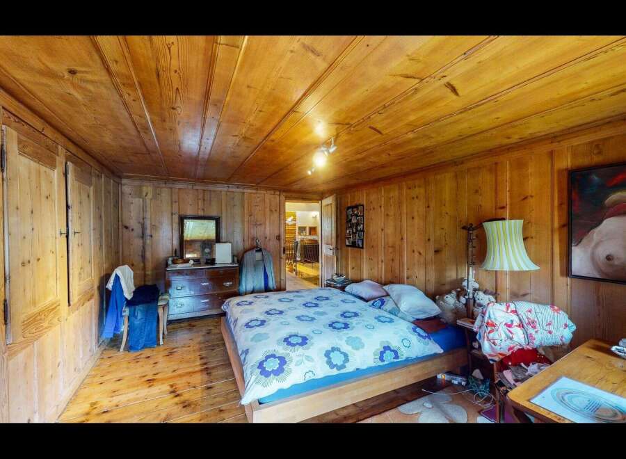 Step into this charming bedroom, featuring warm wooden walls and a cozy atmosphere.