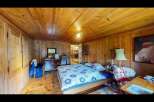Step into this charming bedroom, featuring warm wooden walls and a cozy atmosphere.