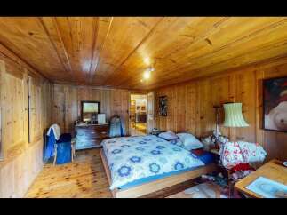 Step into this charming bedroom, featuring warm wooden walls and a cozy atmosphere.
