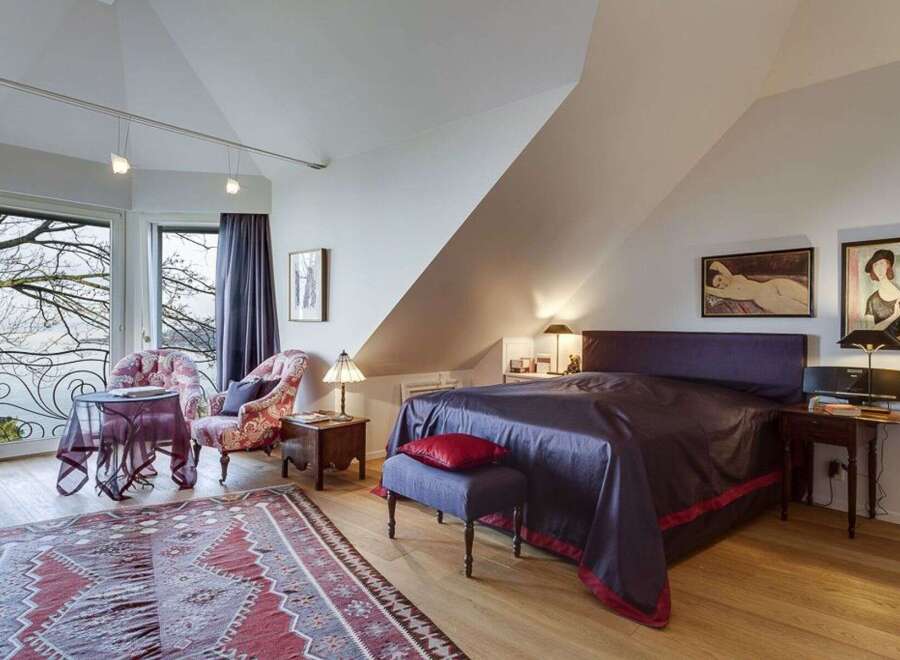 This stunning bedroom boasts a unique design with a sloped ceiling and elegant decor.