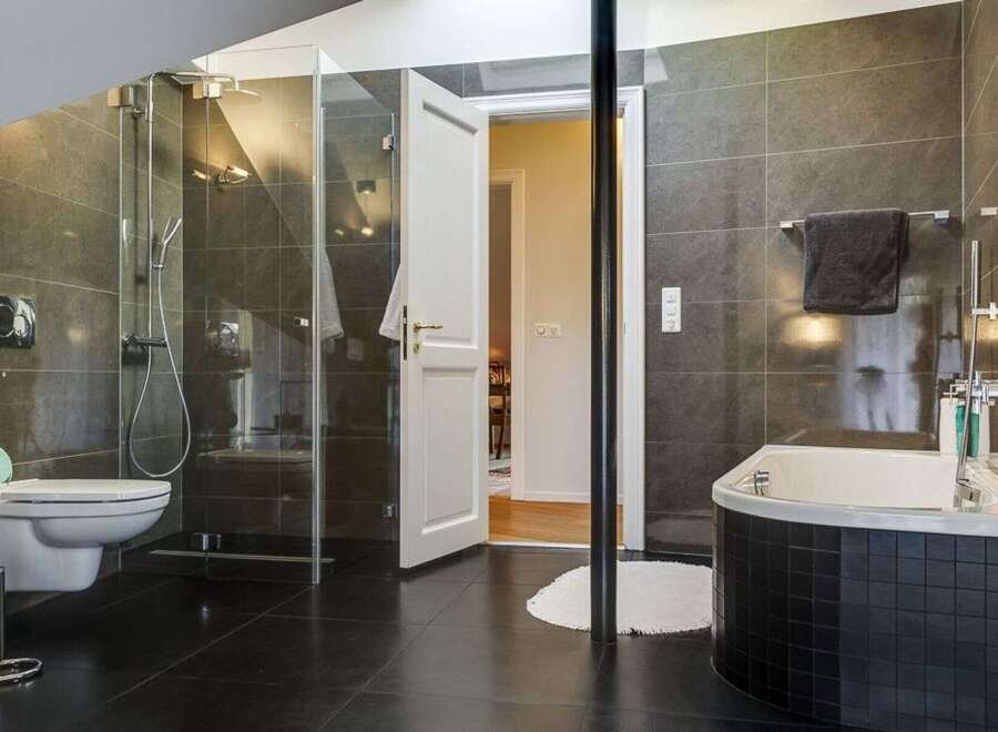 Step into luxury with this stunning bathroom, featuring sleek black tile flooring and a modern glass shower.