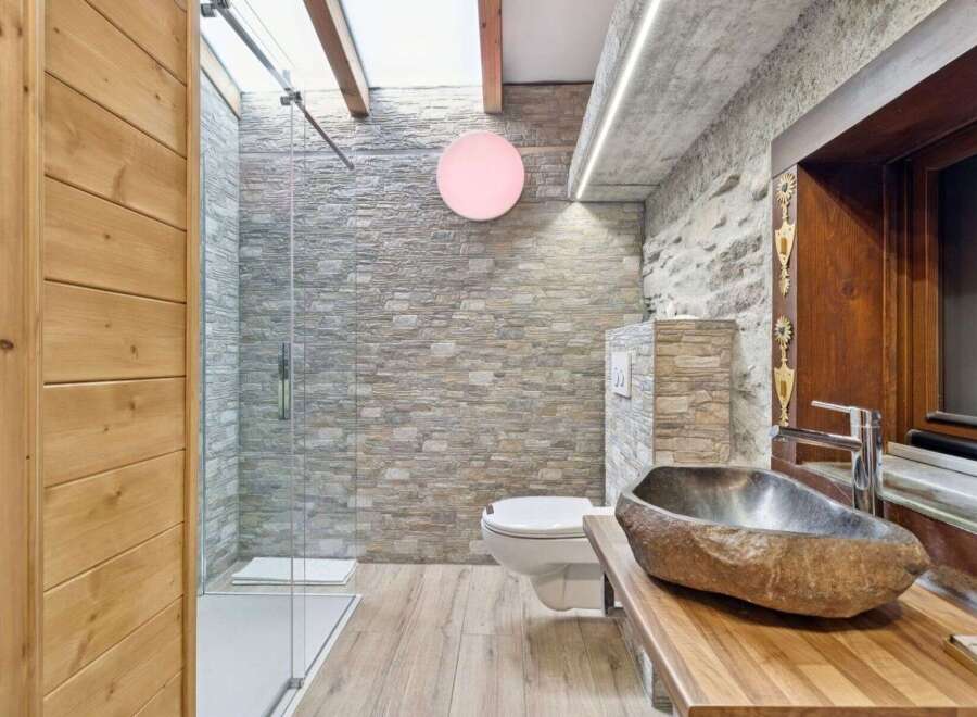 Discover the rustic charm of this stunning bathroom, featuring a unique stone sink and a sleek glass shower.