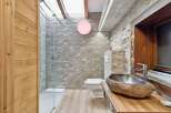Discover the rustic charm of this stunning bathroom, featuring a unique stone sink and a sleek glass shower.