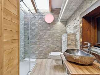 Discover the rustic charm of this stunning bathroom, featuring a unique stone sink and a sleek glass shower.