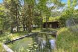 Discover a serene retreat with this stunning property, featuring a picturesque pond surrounded by lush greenery.