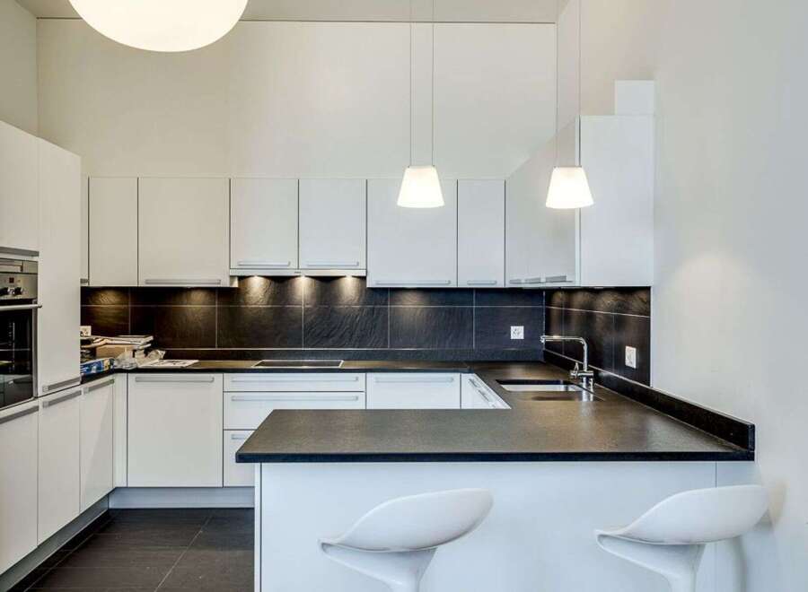 This modern kitchen boasts sleek white cabinetry and a contrasting dark countertop, creating a stylish and functional space.