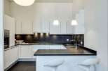 This modern kitchen boasts sleek white cabinetry and a contrasting dark countertop, creating a stylish and functional space.