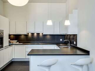 This modern kitchen boasts sleek white cabinetry and a contrasting dark countertop, creating a stylish and functional space.