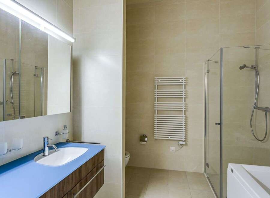 This modern bathroom features a sleek design with a blue countertop and a wooden vanity.