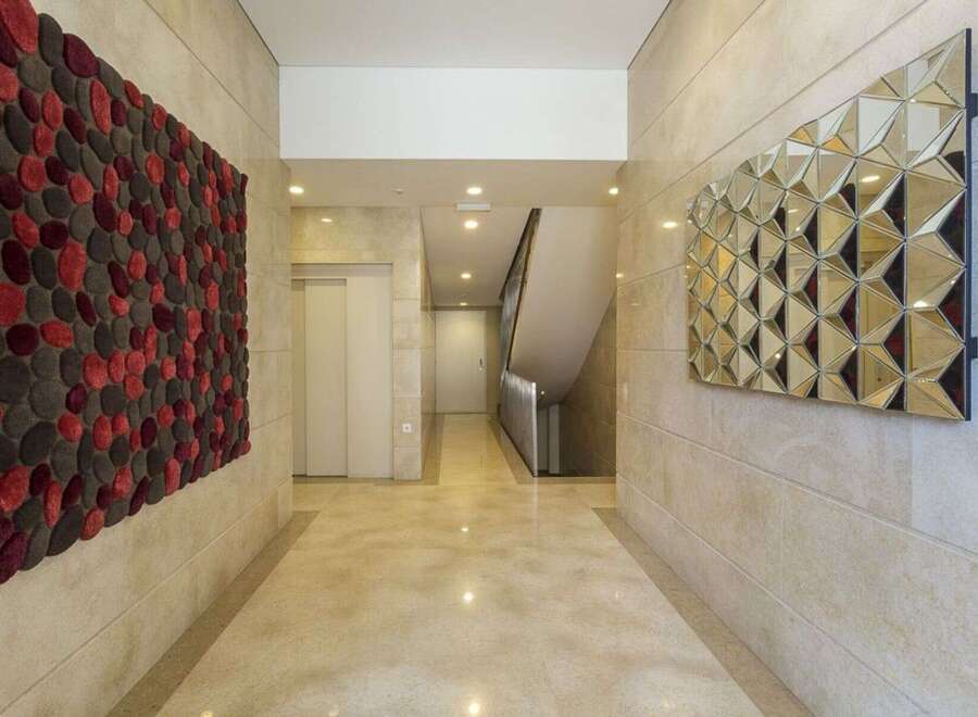 This stunning hallway showcases modern design with its geometric mirror and textured wall art.