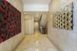 This stunning hallway showcases modern design with its geometric mirror and textured wall art.