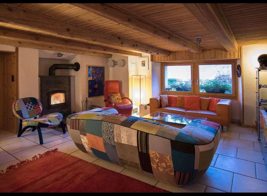 Step into this cozy living space, featuring a unique patchwork sofa and a warm fireplace, perfect for relaxing evenings.