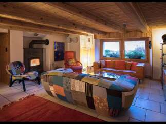 Step into this cozy living space, featuring a unique patchwork sofa and a warm fireplace, perfect for relaxing evenings.