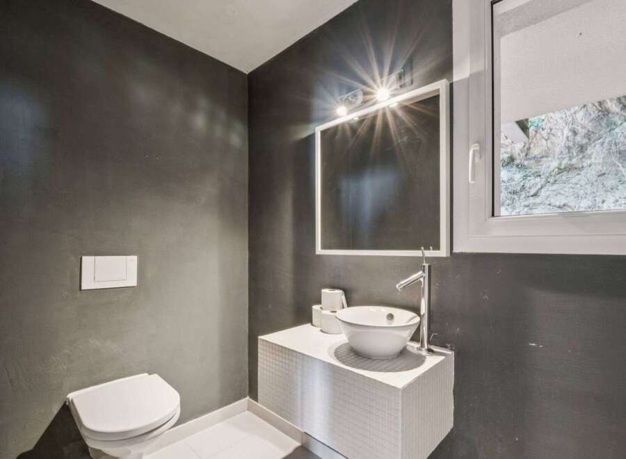 This modern bathroom boasts a sleek design with dark gray walls and a pristine white sink.