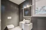 This modern bathroom boasts a sleek design with dark gray walls and a pristine white sink.