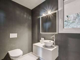 This modern bathroom boasts a sleek design with dark gray walls and a pristine white sink.
