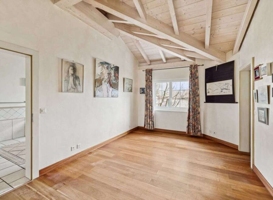This stunning property boasts a unique architectural design with exposed wooden beams and a vaulted ceiling, creating an airy and spacious feel.