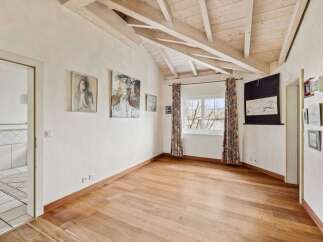 This stunning property boasts a unique architectural design with exposed wooden beams and a vaulted ceiling, creating an airy and spacious feel.