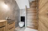 Step into a modern bathroom oasis! This stunning space features a sleek, wall-mounted toilet and a stylish wooden vanity with a stone sink.