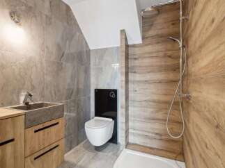 Step into a modern bathroom oasis! This stunning space features a sleek, wall-mounted toilet and a stylish wooden vanity with a stone sink.