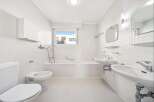 This bright and airy bathroom features a clean, minimalist design with white tile walls and flooring.