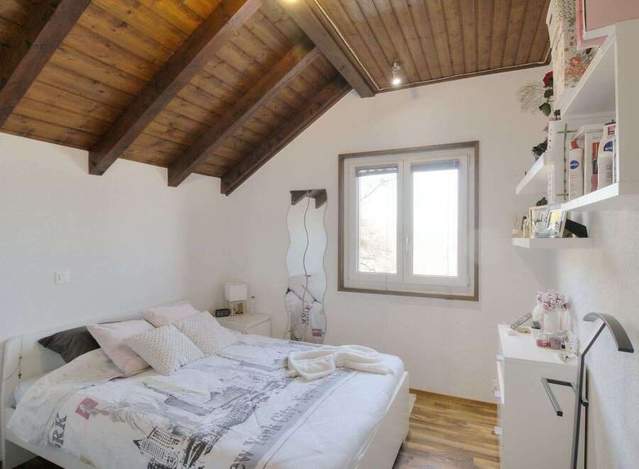 This charming bedroom boasts a unique architectural design with a wooden sloped ceiling, creating a cozy and inviting atmosphere.