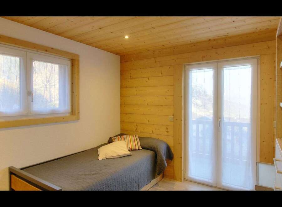 This cozy bedroom features a comfortable single bed with a stylish gray comforter and decorative pillows.