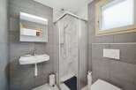 This modern bathroom features a sleek design with gray tiled walls and a glass shower enclosure.