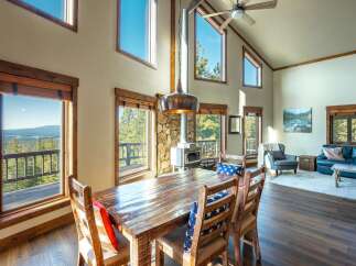 This stunning property boasts a rustic charm with its wooden dining table and chairs, perfect for family gatherings.