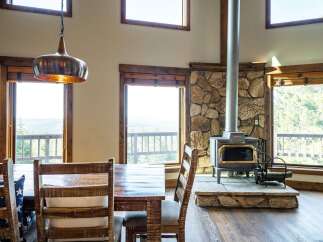 Experience the charm of this stunning property, featuring a cozy dining area with a rustic wooden table and chairs.