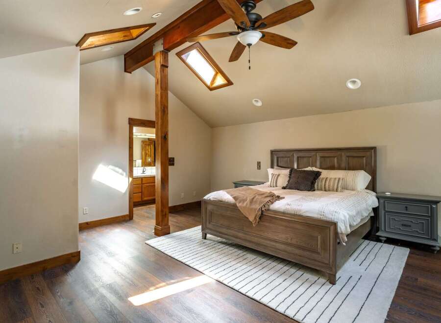 This stunning bedroom boasts a unique design with exposed wooden beams and a skylight, creating a warm and inviting atmosphere.