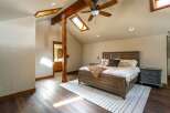 This stunning bedroom boasts a unique design with exposed wooden beams and a skylight, creating a warm and inviting atmosphere.