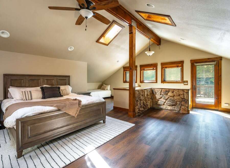 This stunning bedroom boasts a unique architectural design with exposed wooden beams and a vaulted ceiling, creating a cozy and inviting atmosphere.