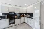 This modern kitchen boasts sleek, white cabinetry and a contrasting black countertop, creating a stylish and functional space.