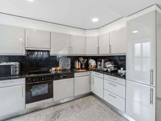 This modern kitchen boasts sleek, white cabinetry and a contrasting black countertop, creating a stylish and functional space.