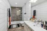 Step into a modern bathroom oasis! This stylish space features sleek white tiles, a walk-in shower with a glass door, and a contemporary vanity.