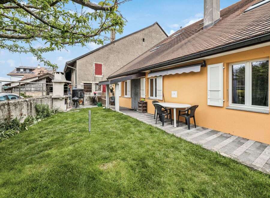 Discover the charm of this inviting property, featuring a well-maintained lawn and a cozy outdoor dining area.