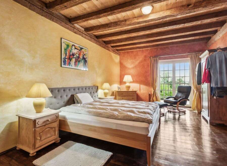 This charming bedroom boasts a rustic aesthetic with exposed wooden beams and warm, inviting colors.