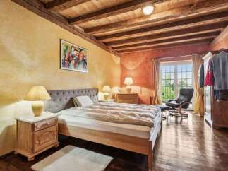 This charming bedroom boasts a rustic aesthetic with exposed wooden beams and warm, inviting colors.