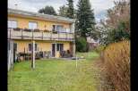 This charming property features a two-story yellow house with a balcony, perfect for enjoying the outdoors.