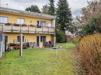 This charming property features a two-story yellow house with a balcony, perfect for enjoying the outdoors.