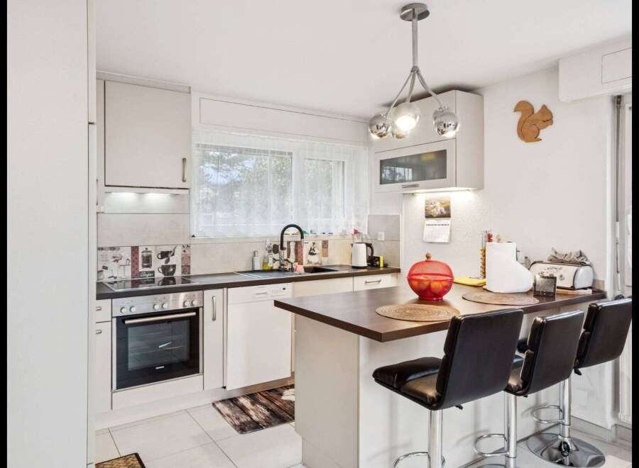 This charming kitchen boasts a modern design with sleek white cabinetry and a contrasting dark countertop.